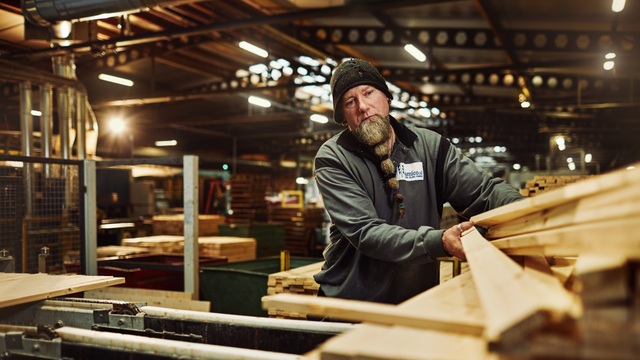 Een man die hout aan het verplaatsen in zijn werkplaats.